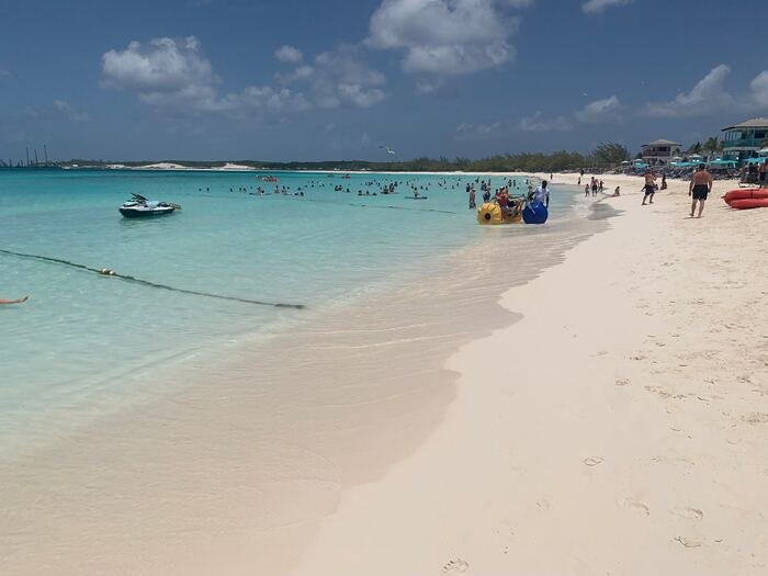 Turquoise water and white sand beach full of travelers